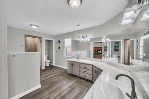 Bathroom featuring a shower, wood-type flooring, vanity, toilet, and a textured ceiling