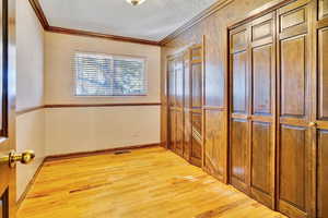 Corridor with crown molding, light hardwood / wood-style flooring, and a textured ceiling