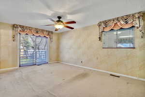 Carpeted empty room with ceiling fan and a textured ceiling