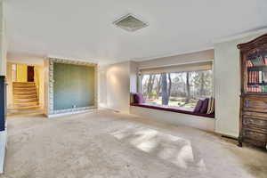 Unfurnished living room featuring crown molding and carpet