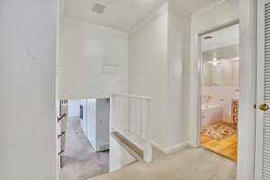 Hallway with light carpet, ornamental molding, and a textured ceiling