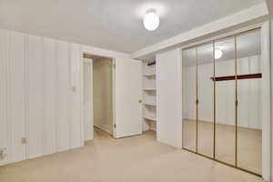 Unfurnished bedroom with light colored carpet and a textured ceiling