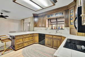 Kitchen featuring sink, tasteful backsplash, tile countertops, kitchen peninsula, and black appliances