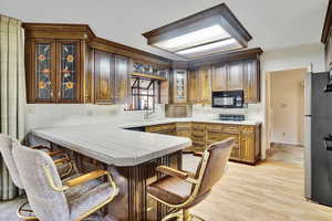 Kitchen with a kitchen bar, sink, tile countertops, kitchen peninsula, and black appliances