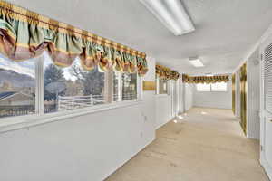 Hall featuring a textured ceiling and carpet flooring