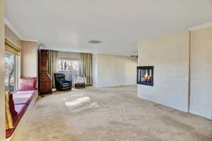 Interior space featuring ornamental molding, light carpet, and a fireplace