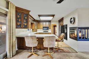 Kitchen with sink, a kitchen bar, black appliances, brick wall, and kitchen peninsula