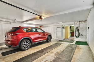 Garage with a garage door opener and white fridge