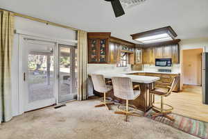 Kitchen featuring ceiling fan, stainless steel fridge, a kitchen bar, and kitchen peninsula