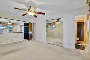 Unfurnished bedroom featuring connected bathroom, ceiling fan, light carpet, a textured ceiling, and a closet