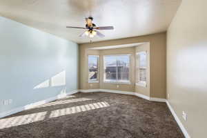 Carpeted spare room with a textured ceiling and ceiling fan