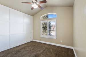 Carpeted spare room with ceiling fan, lofted ceiling, and a wealth of natural light