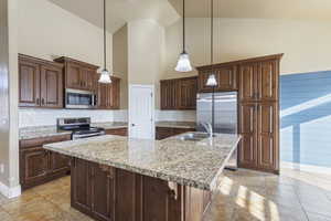 Kitchen featuring sink, hanging light fixtures, an island with sink, and appliances with stainless steel finishes