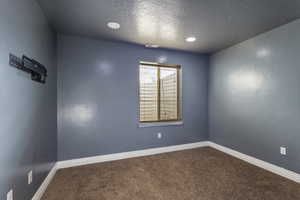 Carpeted empty room with a textured ceiling