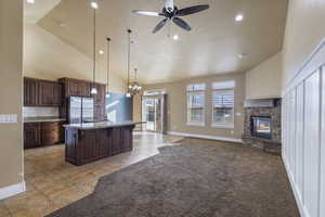 Kitchen featuring pendant lighting, stainless steel refrigerator, a kitchen island with sink, a kitchen breakfast bar, and light colored carpet