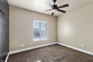 Carpeted spare room featuring ceiling fan