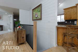 Kitchen featuring sink, wooden walls, light hardwood / wood-style floors, and backsplash