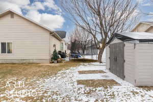 View of snow covered exterior featuring a storage unit and a trampoline