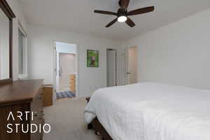 Carpeted bedroom featuring ceiling fan and connected bathroom