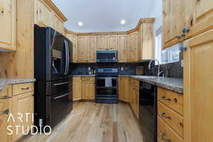 Kitchen with sink, tasteful backsplash, black appliances, light hardwood / wood-style floors, and light brown cabinetry