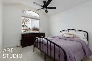 Bedroom with ceiling fan, light colored carpet, and vaulted ceiling