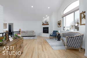 Living room featuring a large fireplace, high vaulted ceiling, and light hardwood / wood-style flooring