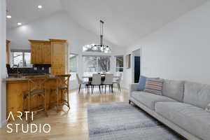 Living room with high vaulted ceiling, sink, a chandelier, and light wood-type flooring