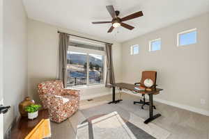 Carpeted home office featuring ceiling fan and a healthy amount of sunlight