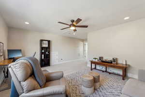 Carpeted living room featuring ceiling fan