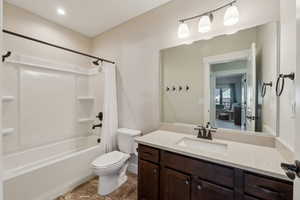 Full bathroom with vanity, shower / bath combination with curtain, tile patterned floors, and toilet