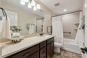 Full bathroom with vanity, shower / tub combo with curtain, and toilet