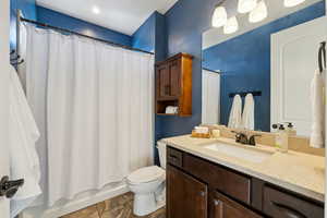 Full bathroom with vanity, shower / tub combo with curtain, and toilet