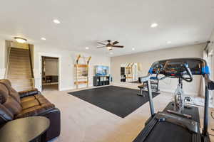 Exercise area with ceiling fan and light colored carpet