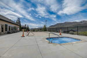 View of swimming pool featuring a community hot tub, a mountain view, and a patio area