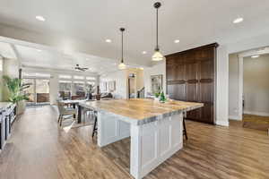 Kitchen featuring dark brown cabinetry, pendant lighting, a breakfast bar, and a center island