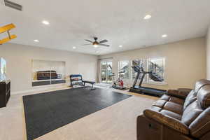 Exercise area with ceiling fan and light colored carpet