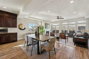 Dining space featuring a tray ceiling, ceiling fan, and light hardwood / wood-style flooring