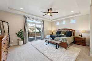 Carpeted bedroom with access to outside, a raised ceiling, and ceiling fan