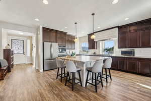 Kitchen with pendant lighting, light hardwood / wood-style floors, a center island, and appliances with stainless steel finishes