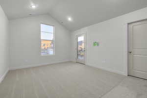 Carpeted empty room featuring lofted ceiling