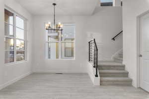 Stairs with hardwood / wood-style floors and a notable chandelier