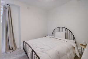 Bedroom with ceiling fan and light colored carpet