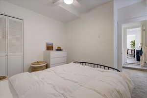 Carpeted bedroom with ceiling fan and a closet