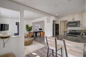 Kitchen featuring electric stove, a breakfast bar area, light hardwood / wood-style flooring, black refrigerator, and kitchen peninsula