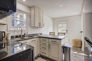 Kitchen featuring sink, electric range oven, cream cabinets, kitchen peninsula, and light wood-type flooring