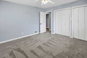 Unfurnished bedroom featuring carpet, two closets, and ceiling fan