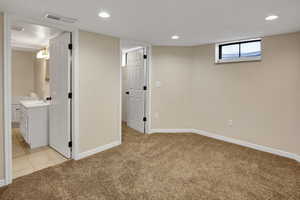 Basement featuring sink and light colored carpet