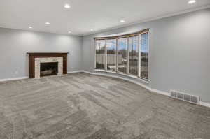 Unfurnished living room featuring crown molding, a high end fireplace, and carpet flooring