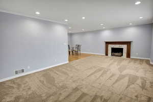 Unfurnished living room featuring crown molding, a high end fireplace, and light carpet