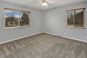 Carpeted spare room featuring a wealth of natural light and ceiling fan